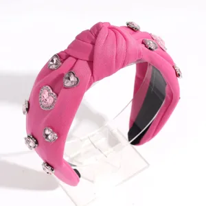 Vue rapprochée du serre-tête en tissu rose orné de brillants strass en forme de cœur.