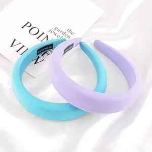 Detailed view of wide padded solid color velvet hairbands in light blue and purple.