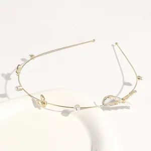 Close-up of thin gold metal hair hoop adorned with delicate pearls and sparkling rhinestones.
