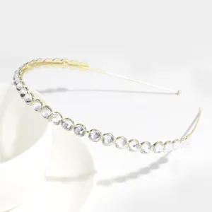 Close-up detail of a minimalist gold-toned metal headband adorned with sparkling clear rhinestones.