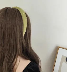 Vue détaillée d'un élégant serre-tête en satin vert avec strass et design de tête surélevé.