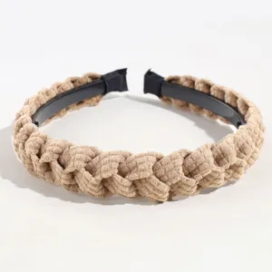 Detalle de diadema trenzada marrón con textura de pana suave y aro interior de plástico negro.