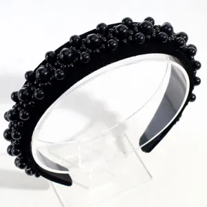 Detalle de primer plano de la diadema de terciopelo negro con cuentas de varios tamaños.