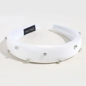 Détail en gros plan du serre-tête en satin blanc rembourré avec des strass étincelants.