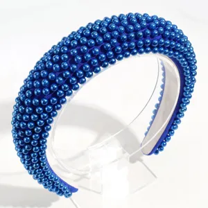 Primo piano dettagliato del cerchietto imbottito di perle blu royal con texture raffinata.