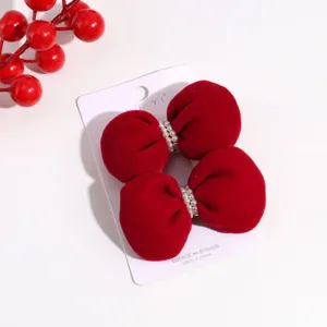 Detailed close-up view of red velvet bow hair clip featuring elegant pearl embellishments.