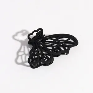 Vista detallada de pinza para pelo de mariposa negra, accesorio mate con diseño calado.