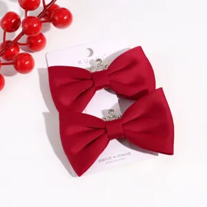 Detailed view of red velvet bow hair clip with rhinestone crown detail, winter hair accessory.