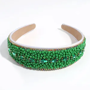 Detailed view of the wide beaded headband featuring sparkling green rhinestones and elegant design.