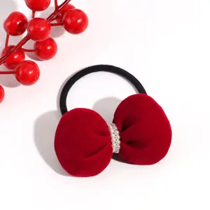 Closeup of red velvet bow hair tie with pearl center knot on a clean white background.