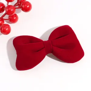 Close-up detail of the red velvet bow hair clip, showing soft texture and festive winter style.