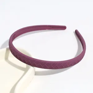 Primo piano di un sottile cerchietto per capelli viola in plastica con trama elegante.