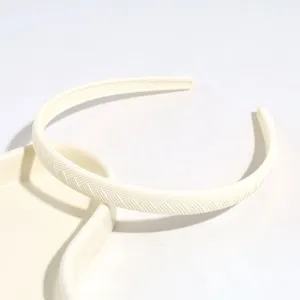 Inquadratura dettagliata di un cerchietto minimalista in plastica bianca a spina di pesce.