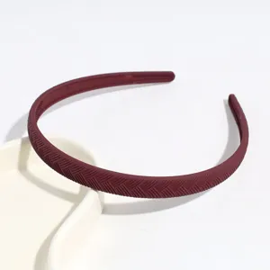Vista dettagliata del cerchietto in plastica rosso scuro con righe diagonali, design minimal.