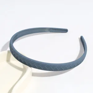 Vista dettagliata del cerchietto in plastica grigio-blu con elegante trama a spina di pesce.