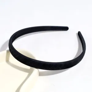 Primo piano dettaglio del cerchietto per capelli nero in plastica sottile testurizzato.