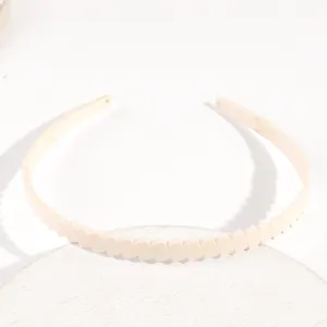 Primo piano dettaglio del cerchietto sottile in plastica da 1.3cm a strisce beige.