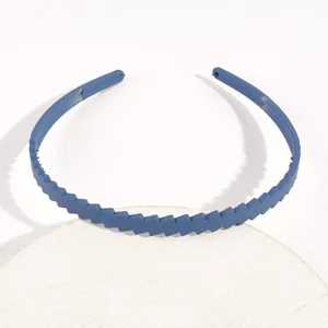 Dettaglio della fascia per capelli in plastica blu, che mostra la superficie strutturata diagonale.