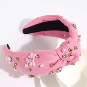 Détail en gros plan du serre-tête noué rose avec des strass étincelants et des perles.