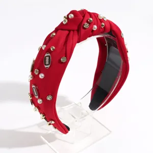 Detailed view of red knotted fabric headband decorated with pearls, rhinestones and football charms.