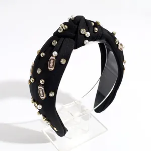 Detail view of a stylish black knotted headband adorned with pearls, rhinestones and football charms.