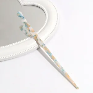 Elegant blue white swirl acetate hair stick resting on a white decorative mirror detail view.