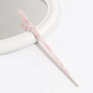 Closeup detail of a pink marbled acetate hair stick, elegant minimalist hair accessory.