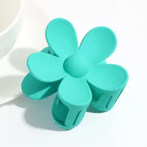 Close up of turquoise matte flower hair claw clip, delicate floral design for women hair styling.