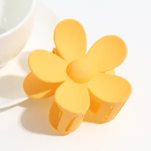 Close-up of yellow matte flower hair claw clip, cute macaron hair accessory detail view.
