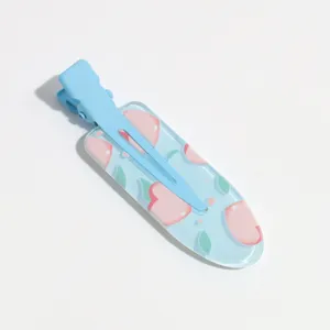 Detail shot of blue duckbill hair clip with sweet peach pattern, cute fruit style accessory.