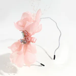 Detail shot of elegant pink chiffon flower headband with crystals and pearls for banquet.