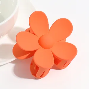 Matte orange flower hair claw clip close up view, lovely hair accessories for daily styling.