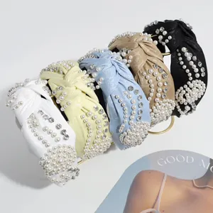 Primer plano de elegantes diademas con nudo adornadas con perlas falsas y brillantes.