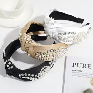 Vista detallada de elegantes diademas nudo con perlas y pedrería en negro, blanco y kaki.