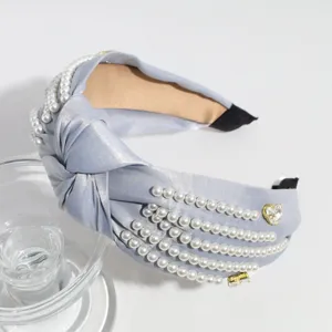 Close-up detail shot of the wide satin knotted headband with elegant pearl and rhinestone rows.