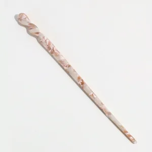 Detailed view of a stylish acetate hair stick with a chic twisted design and marbled pattern.