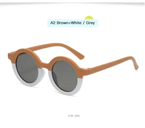 Vista detallada de gafas de sol redondas retro para niños, montura marrón-blanca y lentes.