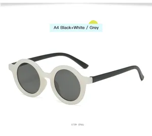 Primer plano de gafas de sol redondas infantiles con montura blanca y patillas negras.