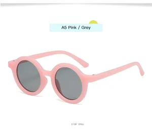 Gafas de sol redondas para niños con montura rosa y lentes grises ideales para exteriores.