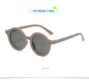 Gafas de sol redondas vintage para niños vista detallada con montura marrón y cristales grises.