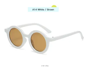 Primer plano de gafas de sol infantiles retro redondas, montura blanca con lentes marrones.