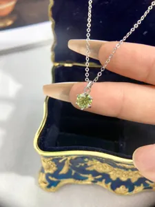 Detail view of a classic six-prong solitaire pendant necklace with a green gem on silver chain.