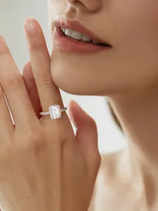 Nahaufnahme Detailaufnahme des Smaragdschnitt Moissanite Halo Rings am Frauenfinger.
