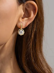 Close-up detail of luxury gold-plated halo drop earrings with sparkling round moissanite diamonds.