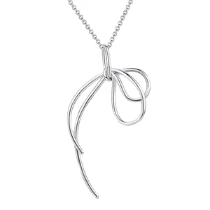 Gros plan du pendentif collier nœud en fil d'argent montrant le délicat design de ruban abstrait.