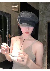 Vintage dark grey newsboy hat detail showing metal chain and safety pin side accessory.