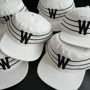 Detailed view of white corduroy flat top riding cap with black gothic letter embroidery.