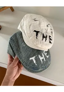 Nahaufnahme Detailansicht von vintage gewaschenen Jeans Flatcaps mit auffälligem Buchstaben.