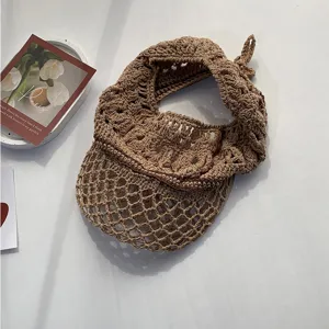 Detalle del sombrero de sol de ganchillo marrón, con textura de red y lazo trasero.