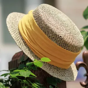 Close-up of a French retro flat-top straw hat with yellow ribbon on wooden post, outdoor detail.